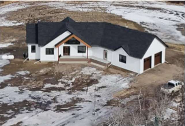 Aerial view of the Powder Ridge home with dark roof and white siding on a snowy lot